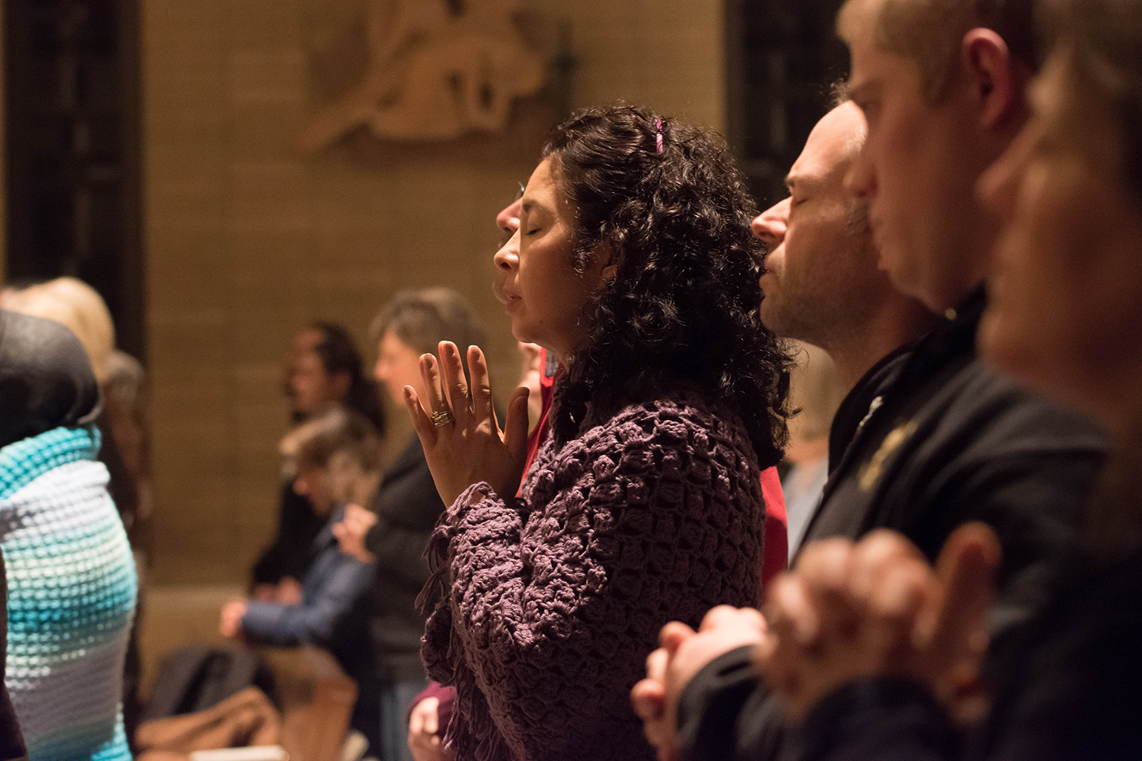 Woman praying with closed eyes in group at a church.